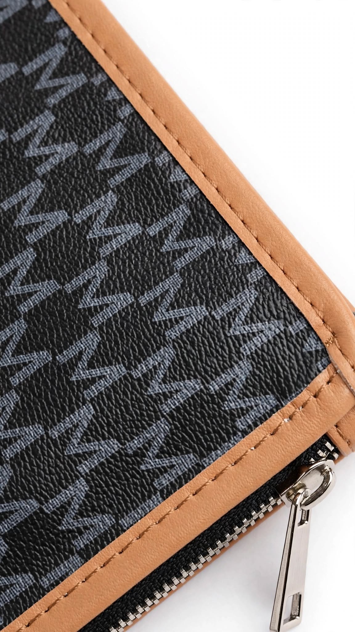 Close up of ZORANI wristlet pouch showing textured monogram leather and silver zipper